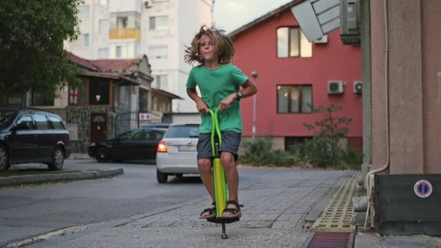 A boy joyfully performs tricks on a pogo stick, experiencing excitement and happiness