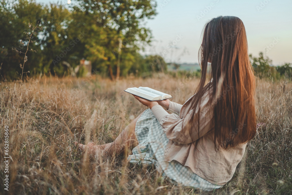 Wall mural girl with a bible in her hands in nature, evening prayer and worship