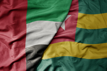 big waving realistic national colorful flag of united arab emirates and national flag of togo .