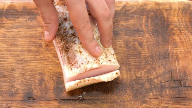 Slicing of salted pork fatback on cutting board, close-up. Ukrainian traditional food - salo