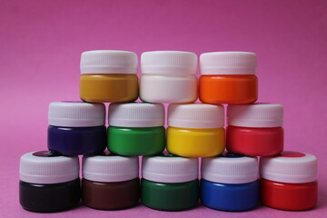 Multi-colored paint in jars, acrylic oil, gouache, tempera, laid out in a slide on top of each...