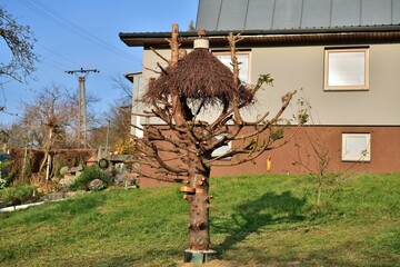 Large bird feeder with a roof made of branches and nesting box