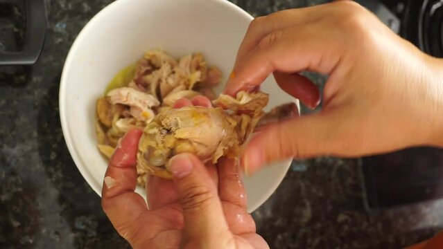 Making Shredded Chicken, Process Boiled Chicken Breast into Pieces. Woman's hand shreds the cooked chicken.