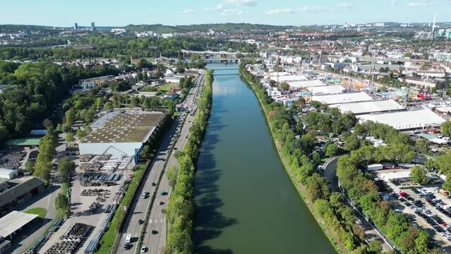 Eine Drohnenaufnahme fliegend &uuml;ber den Neckar in Stuttgart, links daneben eine befahrene Autobahn, rechts daneben der Stuttgarter Wasen in Betrieb.