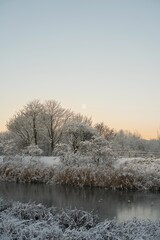 Idyllic winter scene of a tranquil river covered in a layer of ice, illuminated by the setting sun