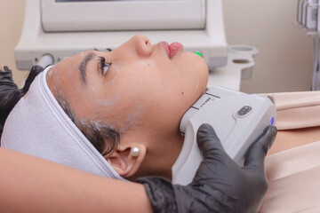 A young woman undergoing HIFU treatment for her jawline. High Intensity Focused Ultrasound technology. At a skin care, dermatologist or aesthetic clinic.
