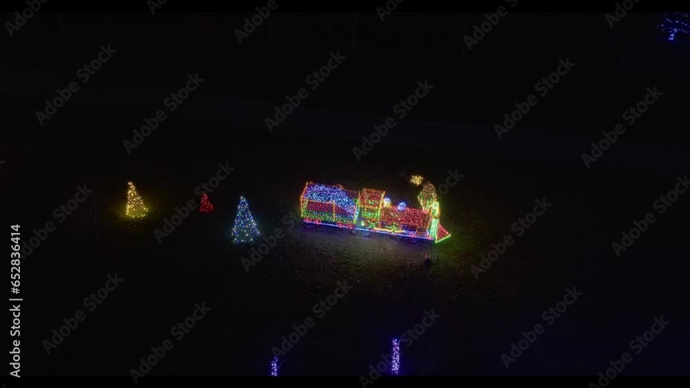 Poster drone zooming in view of a large moving led steam engine with puffing smoke, in a christmas display