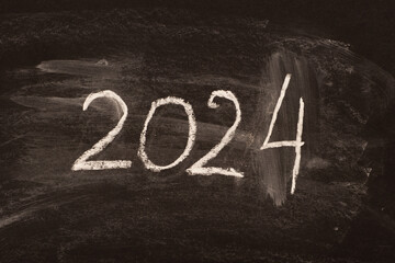 The number 2024 is written in chalk on a blackboard as a symbol of the coming New Year. - obrazy, fototapety, plakaty