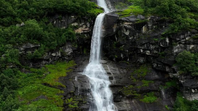 Drone view over cascade Brekkefossen Waterfall on green mountain in Norway