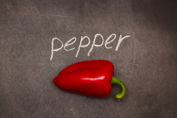 The word pepper with a red sweet vegetable written on the chalk board is written on the chalk.