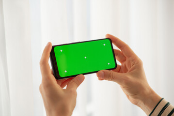 girl holding a phone with a green screen at home. Device. Smartphone. Social networks