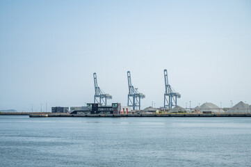 Three blue freight cranes at Aarhus Harbor Port, view from the distance, clear sky, denmark
