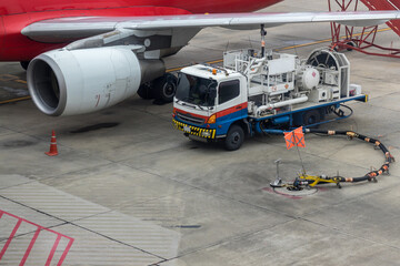 Aircraft refueling by high pressure fuel supply truck. Refueling operation of large widebody passenger aircraft standing on airport's parking place . Refueling of the airplane before flight..