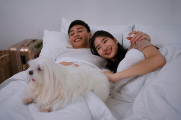 Young couple together in bedroom with dog.