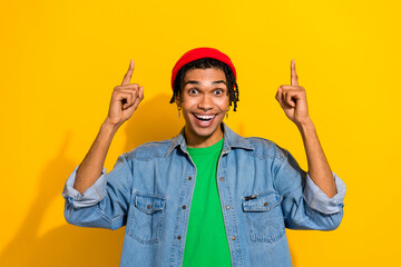 Photo of excited cheerful guy wear trendy jeans jacket two arms demonstrate low price offer empty space isolated on yellow color background