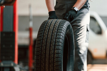 Rolling the wheel. Man is works in the automobile repairing salon