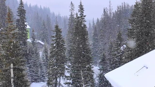 Winter in the mountains, slow motion snowing, icicles on the roof