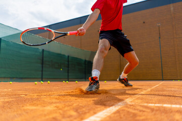 close-up of a tennis player's or instructor's foot on an outdoor court ground dust rising near the shoe