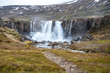 Beautiful Waterfall at Seydisfjordur, Iceland with snow mountains in the background