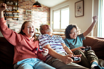 Grandfather is Playfully Defeated by his Grandchildren in a Video Game at Home