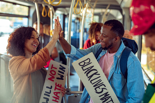 Two young African American friends raising morale by high fiving each other while going to the black lives matter protest together on the bus