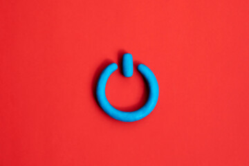Photo of 3d plasticine blue start icon on red background. Power on off, switch or start and stop...
