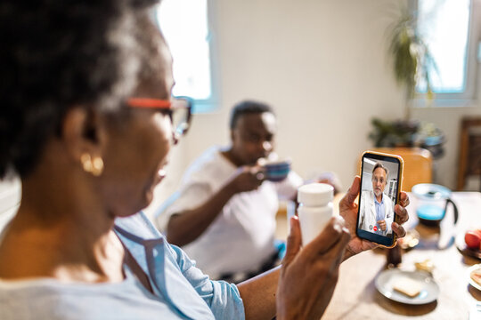 Senior African American woman asking for advice from her doctor about medication on a video call on the smartphone in the kitchen at home