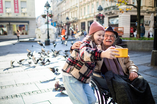 Granddaughter taking a selfie on a smartphone with her grandfather in the city