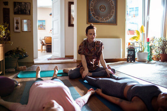 Young and diverse group of female friends doing yoga together in the living room at home