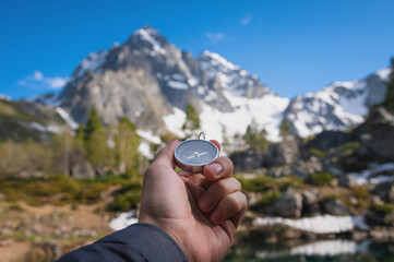 Snow-capped mountains and a tourist hand with an old metal compass in the foreground. Nature reserve, landscape photography
