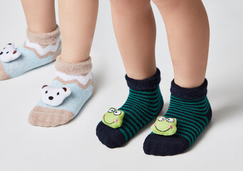  Children wearing pair of socks. Top view to kids foots in mismatched socks sitting on white background. Odd Socks day