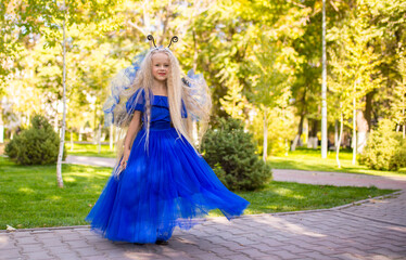 Little girl dressed as a fairy on the background of the park. The concept of a magical holiday....