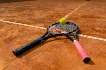 close-up of sports equipment, tennis rackets and balls lie on an outdoor ground court hobby...
