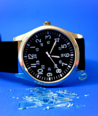 Watch with screen glass cracked on blue background. time concept.
