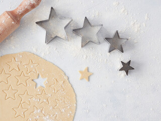 Baking at home for Christmas, dough cut with star-shaped pastry cutters of different sizes. Wooden...