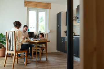 Mother, father, and little daughter having lunch together at home.
