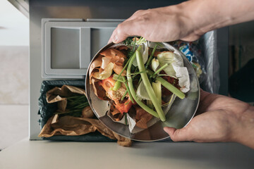 Woman throws vegetable and fruit peels, scrap from food preparation in trash-pack for recycling