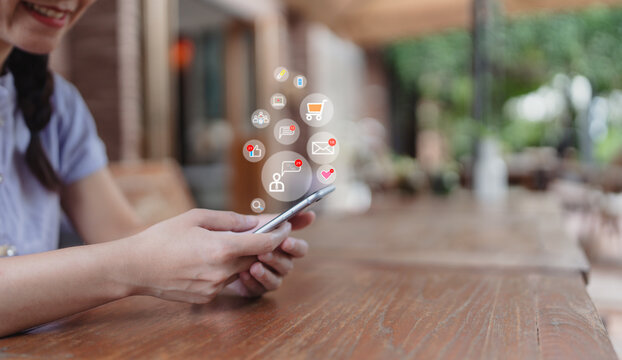 Happy smiling Asian woman spending her free time on social media. Respond  conversation messages via smartphone. Notification icons: Chat, Like, Share, Reply ,feedback Access interactive apps on phone