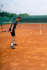 young professional player coach on outdoor tennis court practices strokes with racket and tennis ball