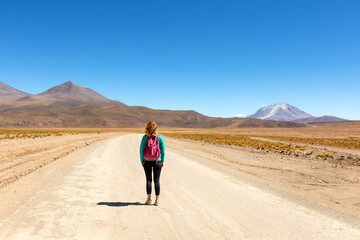 A tourist with a backpack walks along a road leading to an active volcano. Andes Bolivia