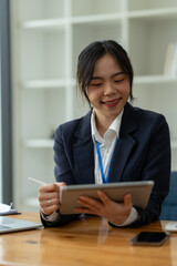 Smiling Asian business woman Delight in the achievements by using the tablet to work with plans, ideas, ideas to present. financial report business plan investment new age concept online