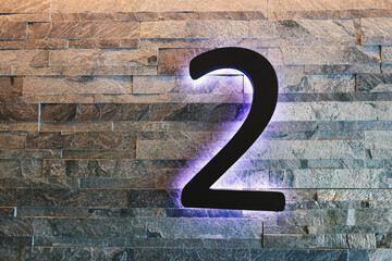 Dark  Neon Font with fluorescent purple tubes  Number 2 on the dark brown brick wall.  Night Show Alphabet.