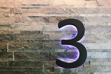 Dark  Neon Font with fluorescent purple tubes  Number 3 on the dark brown brick wall.  Night Show Alphabet.