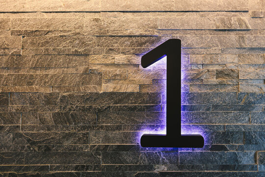 Dark  Neon Font with fluorescent purple tubes  Number 1 on the dark brown brick wall.  Night Show Alphabet. - Powered by Adobe