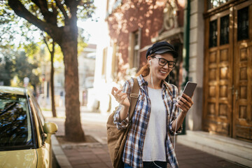 Young Asian student using a smartphone while walking in the city