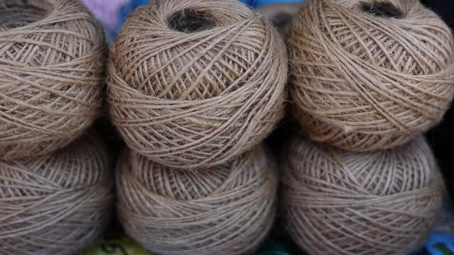 rolls of natural hemp wire for parcel twine, string, packing or diy.fencing strand,polypropylene orange, blue twine.spools in plastic bag,woman hand,market store sale concept.thick rope texture