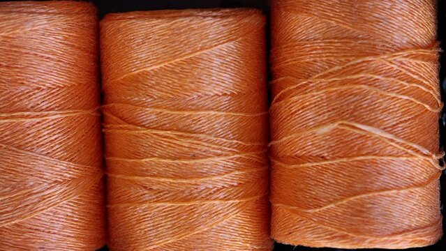 rolls of natural hemp wire for parcel twine, string, packing or diy.fencing strand,polypropylene orange, blue twine.spools in plastic bag,woman hand,market store sale concept.thick rope texture