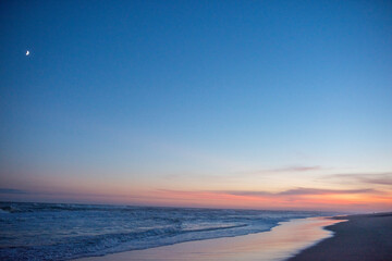 The moon and  sunset over a beach in the hamptons