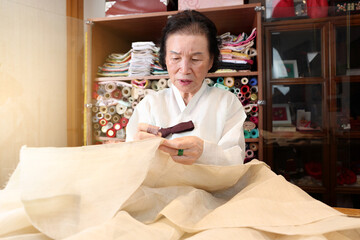 한국 전통복장인 한복 명인이 한복 제작을 위해 바느질을 하고있다