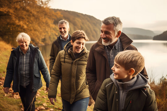 Multi generation family walking by lake on countryside.